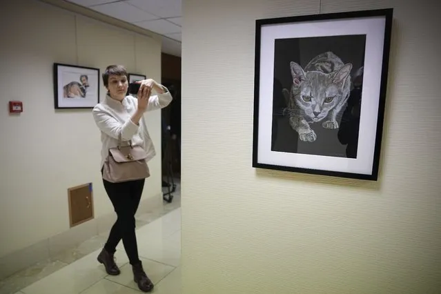 A journalist films with her smartphone during an opening of exhibition of artworks by Russian businessman Viktor Bout, who was sentenced to 25 years in the United States, at the Federation Council of the Federal Assembly of the Russian Federation in Moscow, Russia, Tuesday, November 15, 2022. Russia has sought Bout's release for years and he is believed to be key to a possible prisoner exchange that could free US women's basketball star Brittney Griner. (Photo by Alexander Zemlianichenko/AP Photo)