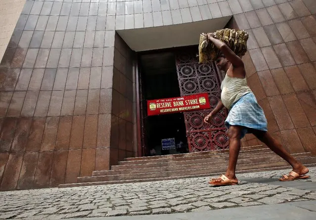 A labourer carrying dry leaves walks past a Reserve Bank of India (RBI) building during a nationwide strike in Kolkata, India September 2, 2016. (Photo by Rupak De Chowdhuri/Reuters)