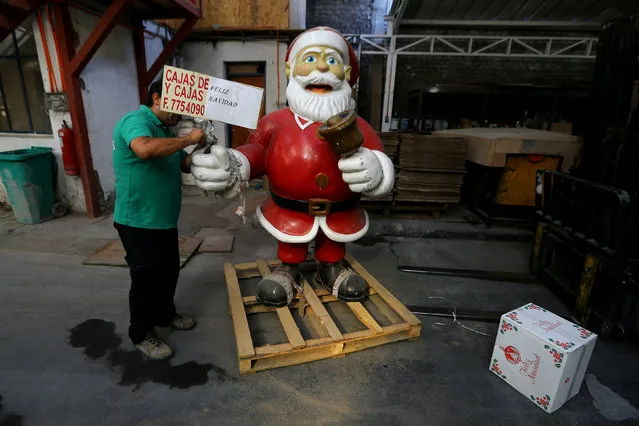 A worker removes tape from a Santa Claus figurine in Santiago, Chile, December 21, 2017. (Photo by Ivan Alvarado/Reuters)