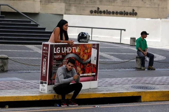A couple who bought a television on sale had their motorcycle towed while shopping in a store during Black Friday sales, in Caracas, Venezuela on November 25, 2022. (Photo by Leonardo Fernandez Viloria/Reuters)