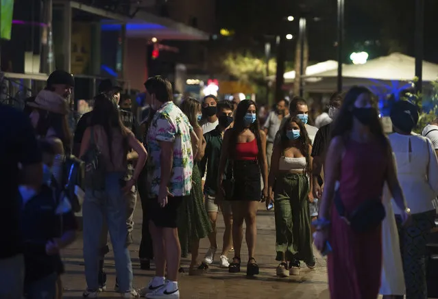 A group of people wearing face masks walk on the street In Fuengirola, near Malaga, Spain, Saturday, August 8, 2020. The increase in Spain of coronavirus outbreaks associated with nightlife has set off alarms in recent days, mainly in tourist areas where pubs and discos are full before the summer tourist campaign. (Photo by Jesus Merida/AP Photo)