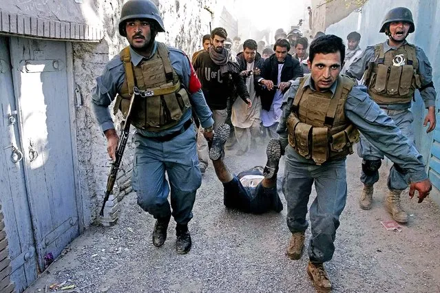 Afghan security forces drag the body of a gunman after he was killed in a clash with police, in downtown Herat, Afghanistan, Tuesday, October 28, 2014. An Afghan police chief says that gunmen attacked a checkpoint Monday in the western city of Herat, killing two police officers. (Photo by Hoshang Hashimi/AP Photo)