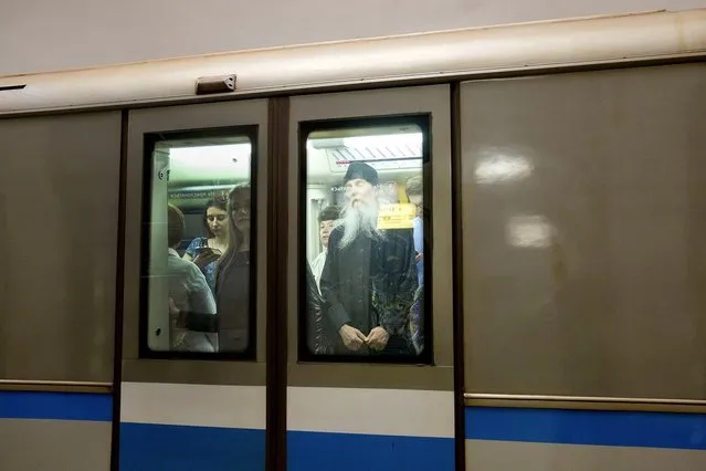 A priest seen through the window of a train. (Photo by Didier Bizet/The Washington Post)