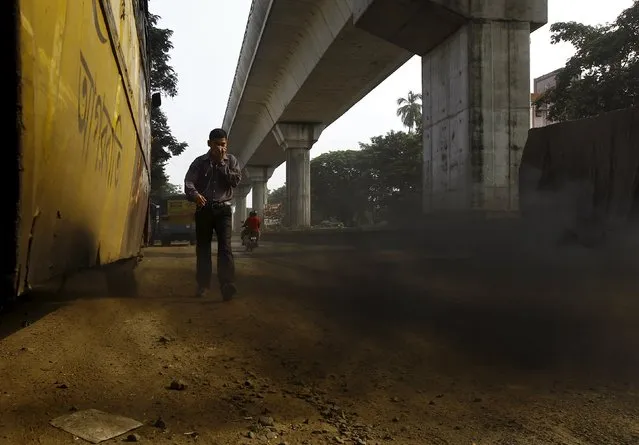 A passenger bus emits smoke as a commuter covers his face on a road in Kolkata, India, October 2, 2015. (Photo by Rupak De Chowdhuri/Reuters)