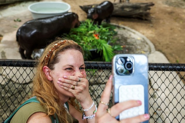 Molly Swindall, 30, who travelled from the United States to meet Moo Deng for the third time, reacts as she takes a selfie with the one-year-old female pygmy hippo, who became a viral internet sensation last year, and her mother Jona, at Khao Kheow Open Zoo in Chonburi province, Thailand, on July 10, 2025. (Photo by Chalinee Thirasupa/Reuters)