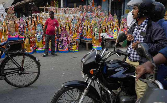 A vendor awaits customers beside a roadside stall selling idols of Saraswati, the Hindu goddess of learning, ahead of its worship scheduled for Thursday in Kolkata, India, Wednesday, January 25, 2023. (Photo by Bikas Das/AP Photo)
