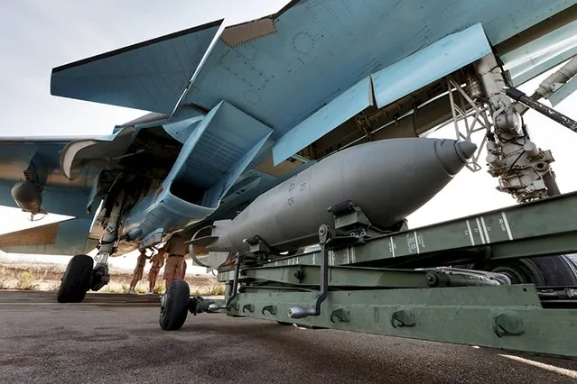 Russian ground staff members work on a Sukhoi Su-34 fighter jet at the Hmeymim air base near Latakia, Syria, in this handout photograph released by Russia's Defence Ministry October 22, 2015. (Photo by Reuters/Ministry of Defence of the Russian Federation)