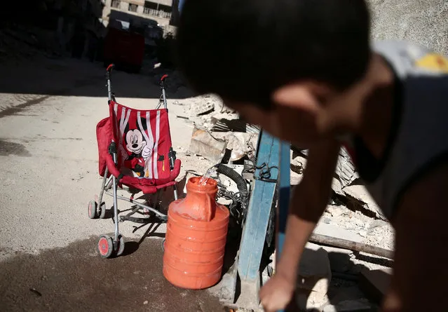 A boy fills a container with water in the rebel-held besieged town of Zamalka, in the Damascus suburbs, Syria September 28, 2016. (Photo by Bassam Khabieh/Reuters)