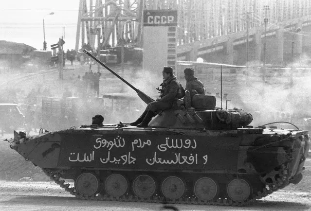 A Soviet tank, part of one of the last Soviet units to leave Afghanistan, crosses the border back into the USSR at Termez, February 1989. In the background is the Friendship Bridge linking the USSR and Afghanistan over the Amu River. (Photo by Reuters/Stringer)