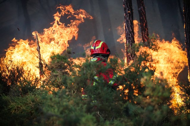 A firefighter is seen next to flames while working to extinguish a wildfire burning in Gondomar, northern Portugal on July 29, 2025. (Photo by Carlos Costa/AFP Photo)