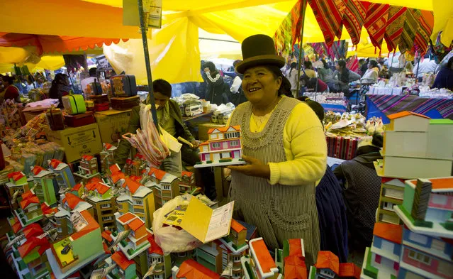 Vendor Maria Luisa sells miniatures homes at the annual Alasita fair in downtown La Paz, Bolivia, Wednesday, January 24. 2018. Thousands people attended the opening day of the fair to buy tiny replicas of things they aspire to acquire during the year, like homes, cars, wealth and love. (Photo by Juan Karita/AP Photo)