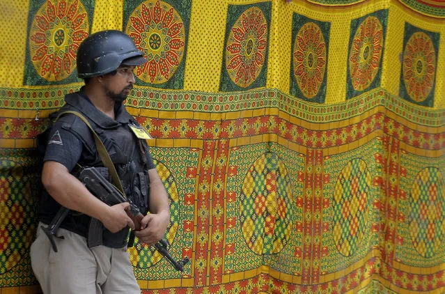 A Pakistani police commando stands guard outside a tent during Shiite Muslims' congregation during the mourning month Muharrum in Peshawar, Pakistan, Tuesday, October 4, 2016. (Photo by K.M. Chaudary/AP Photo)