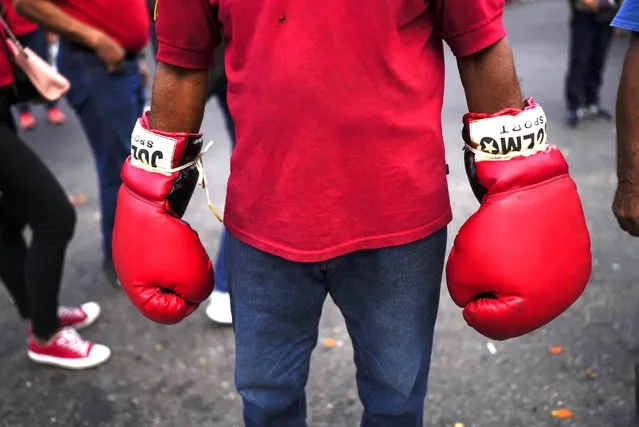 A government supporter wears read boxing gloves during an event marking the anniversary of the coup that overthrew dictator Marcos Perez Jimenez in 1958 in Caracas, Venezuela, Monday, January 23, 2023. (Photo by Ariana Cubillos/AP Photo)