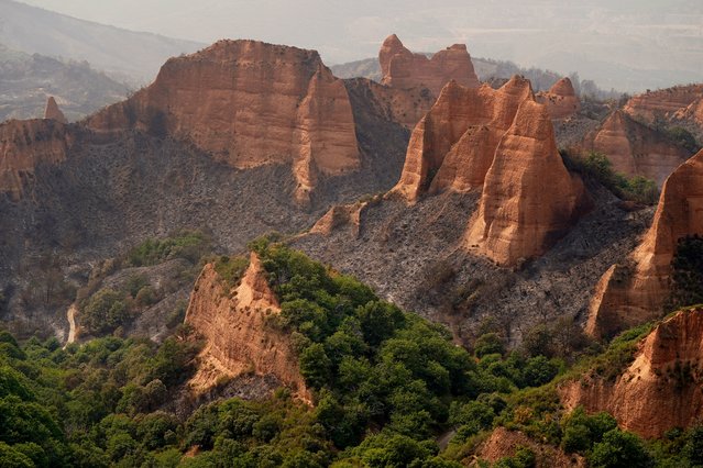 This picture taken from the Orellana viewpoint shows the Roman-era mining site of Las Medulas in the municipality of Carucedo, after a wildfire ravaged the area, on August 11, 2025. Firefighters in northwestern Spain struggled today to contain a wildfire that damaged a Roman-era mining site and forced hundreds of residents to evacuate. The firefighting effort faced "many difficulties" due to high temperatures and winds of up to 40 kilometres per hour (25 mph), said the regional environment minister. The blaze broke out yesterday near the UNESCO World Heritage Site of Las Medulas, a Roman gold-mining area famed for its striking red landscape in northwestern Spain. (Photo by Cesar Manso/AFP Photo)