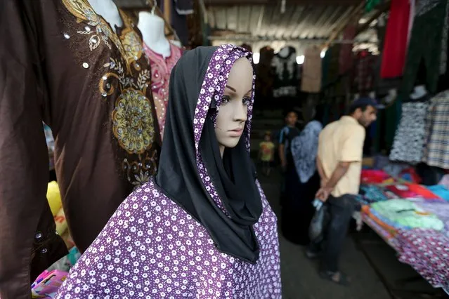 Palestinians shop as a mannequin displaying a headscarf and robe is seen at a market ahead of the Eid al-Adha festival in Khan Younis in the southern Gaza Strip September 23, 2015. (Photo by Ibraheem Abu Mustafa/Reuters)