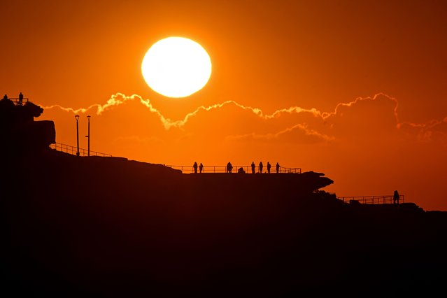 People watch the sunrise overlooking Bondi Beach in Sydney on September 19, 2025. (Photo by Saeed Khan/AFP Photo)