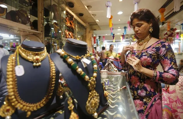 A customer tries a gold necklace at a jewellery showroom on the occasion of Dhanteras, a Hindu festival associated with Lakshmi, the goddess of wealth, at a market in Mumbai, India, November 9, 2015. Hindus purchase ornaments and utensils on the festival, celebrated two days before Diwali, the festival of lights. (Photo by Shailesh Andrade/Reuters)