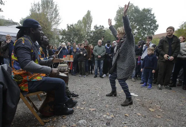 A woman dances as migrants play bongos outside the Montello barracks, in Milan, Italy, Tuesday, November 1, 2016. More than a thousand Italians turned out to welcome a group of migrants who have been moved to a recently purposed military barracks following demonstrations against their presence. (Photo by Luca Bruno/AP Photo)
