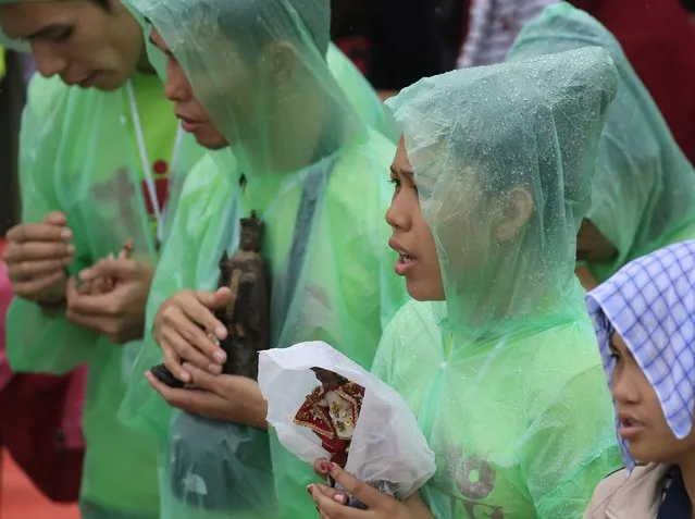 Pilgrims wear raincoats while holding statues of Baby Jesus during Pope Francis' meeting with youths at the University of  Santo Tomas (UST) in Manila January 18, 2015. (Photo by Romeo Ranoco/Reuters)