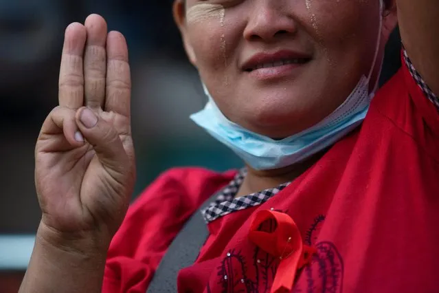 A vendor wearing a red ribbon flashes the three-finger salute as she takes part in a campaign against the military coup in Yangon, Myanmar on February 5, 2021. (Photo by Reuters/Stringer)