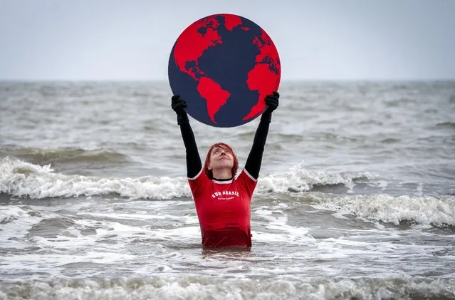Susie Gray, from the Edinburgh Science Festival team, stands in the Firth of Forth at Portobello in Edinburgh on April 21, 2022, holding a giant black and red Earth to highlight the climate emergency and rising sea levels ahead of Earth Day on Friday April 22, 2022. (Photo by Jane Barlow/PA Images via Getty Images)