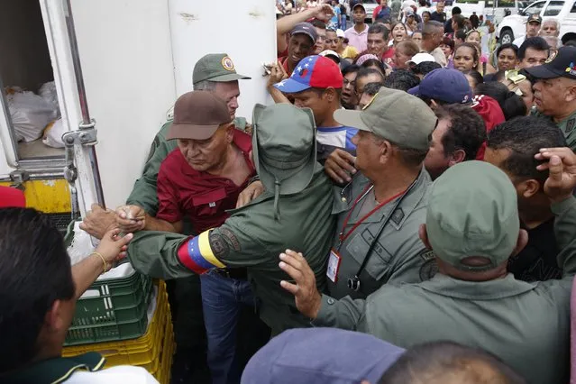 People argue with Venezuelan soldiers as they try to buy chickens at a Mega-Mercal, a subsidized state-run street market, in Caracas January 24, 2015. (Photo by Carlos Garcia Rawlins/Reuters)