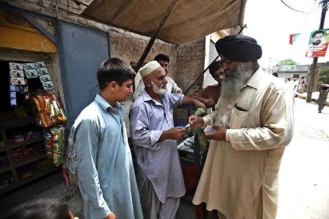In this July 11, 2018, photo, Radesh Singh, right, is one of about 200,000 Sikhs living in Pakistan, talks to local people in his constituency in Peshawar, Pakistan. Despite attacks on his fellow Sikhs by radicals and even by Islamic State insurgents, he is running in elections as an independent. (Photo by Muhammad Sajjad/AP Photo)