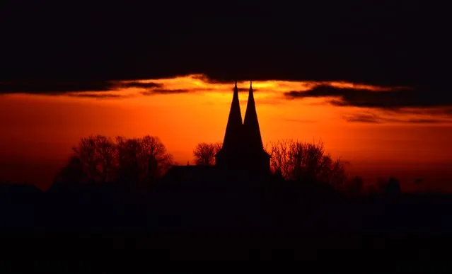 The St. Lawrence Church against a brightly colored morning sky in Hohenhameln, Germany, January 28, 2015. (Photo by Julian Stratenschulte/EPA)