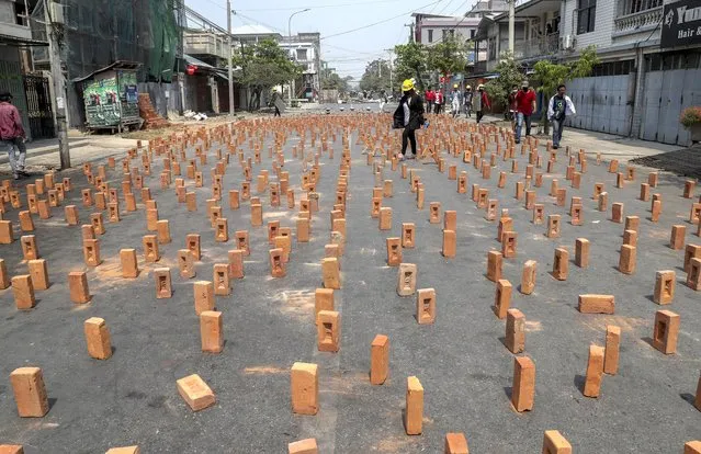 An anti-coup protester walks in a section of a road blocked with bricks in Mandalay, Myanmar, Wednesday, March 10, 2021. Myanmar has been roiled by protests and other acts of civil disobedience since the Feb. 1 coup that toppled elected leader Aung San Suu Kyi's government just as it was to start its second term. (Photo by AP Photo/Stringer)