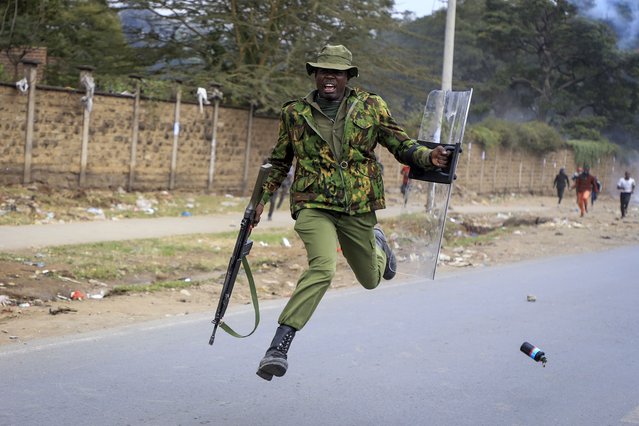 A policeman jumps as he tried to avoid a tear gas grenade thrown back towards police by protesters in the Mathare neighborhood of Nairobi, Kenya Wednesday, July 12, 2023. Kenyans angered by the rising cost of living were back protesting on the streets of the capital, Nairobi, on Wednesday, as they awaited a speech by a longtime opposition leader. (Photo by AP Photo/Stringer)