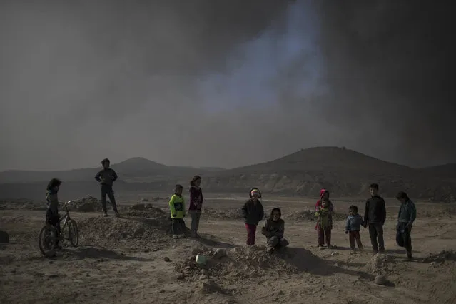 Children stand among smoke from burning oil fields in Qayara, south of Mosul, Iraq, Tuesday, November 22, 2016. (Photo by Felipe Dana/AP Photo)