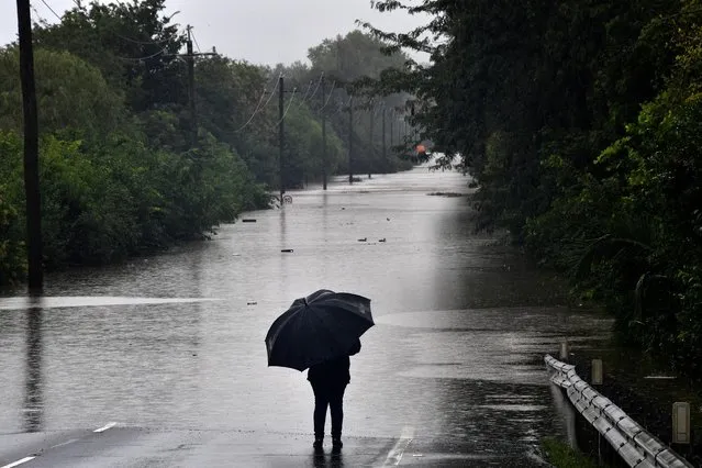 A man looks at a road inundated by floodwaters in Richmond suburb on March 22, 2021, as Sydney braced for its worst flooding in decades after record rainfall caused its largest dam to overflow and as deluges prompted mandatory mass evacuation orders along Australia's east coast. (Photo by Saeed Khan/AFP Photo)