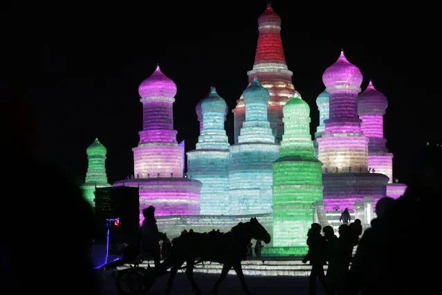People look at ice sculptures illuminated by coloured lights on the opening day of the Harbin International Ice and Snow Festival in the northern city of Harbin, Heilongjiang province, China, January 5, 2016. (Photo by Aly Song/Reuters)