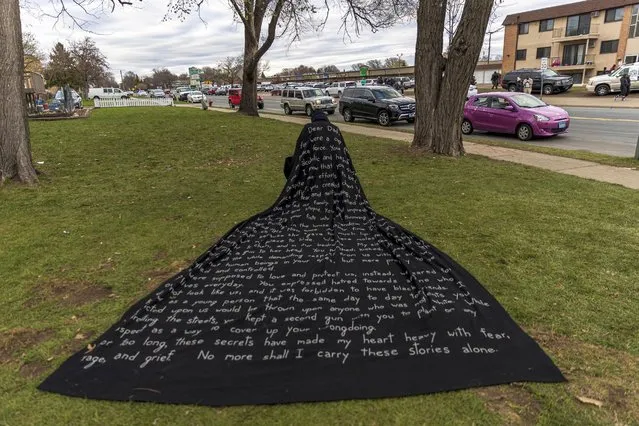 San Francisco-based artist Liney D draws attention to social injustice by wearing a cape with her story written on it, in front of the Brooklyn Central Police Station in Brooklyn Center, Minnesota on April 15, 2021. Kim Potter, the policewoman who shot dead Daunte Wright in a Minneapolis suburb after appearing to mistake her gun for her Taser, was arrested on Wednesday on manslaughter charges. Minneapolis has been roiled by nightly violent protests after Potter's shooting of Wright in his car on Sunday. (Photo by Kerem Yucel/AFP Photo)