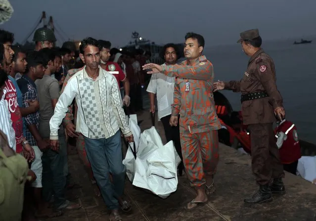 Bangladeshi rescue workers carry the dead body of one of the victims after a river ferry carrying unto 140 passengers capsized Sunday after being hit by a cargo vessel,in Manikganj district, about 40 kilometers (25 miles) northwest of Dhaka, Bangladesh, Sunday, February 22, 2015. (Photo by A. M. Ahad/AP Photo)