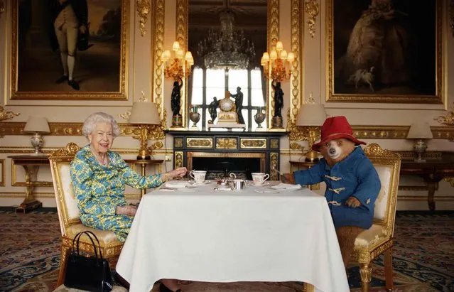 An undated handout photograph released by Buckingham Palace on June 4, 2022, shows Queen Elizabeth II and Paddington Bear having cream tea at Buckingham Palace, taken from a film that was shown at the BBC Platinum Party at the Palace on June 4, 2022. Some 22,000 people and millions more at home are expected at a star-studded musical celebration for Queen Elizabeth II's historic Platinum Jubilee. (Photo by Buckingham Palace/AFP Photo)