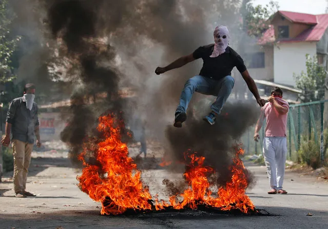 A man in a balaclava jumps over burning debris during a protest against the recent killings in Kashmir, in Srinagar, September 12, 2016. (Photo by Danish Ismail/Reuters)