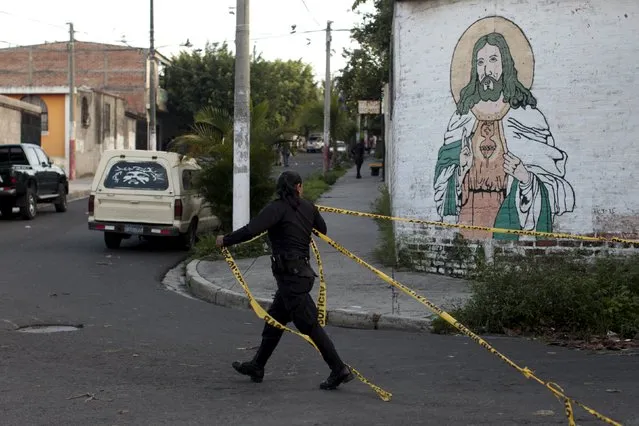 A police officer takes down a yellow police tape at a crime scene in Soyapango, on the outskirts of San Salvador September 26, 2015. In El Salvador the number of homicides surged 70 percent last year, making the central American nation among the most violent countries in the world. Violence and murders have risen steadily since a 2012 truce between the two main street gangs began to fall apart. Months of reporting show killings in the suburbs of the capital, San Salvador, where powerful gangs known as maras control entire neighbourhoods. (Photo by Jose Cabezas/Reuters)
