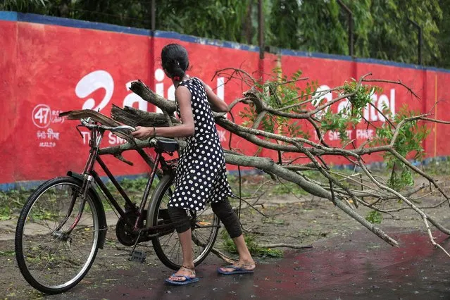 A woman carries fallen branches as Cyclone Yaas makes landfall in Digha, near the Bay of Bengal, south of Kolkata, India, 26 May 2021. (Photo by Piyal Adhikary/EPA/EFE)
