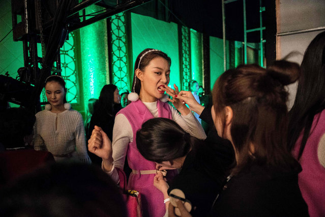 A model (C) tries to remove lipstick from her teeth backstage before the presentation of the Rabbit- Warm collection by Zhuang Ganran during China Fashion Week in Beijing on October 30, 2018. (Photo by Nicolas Asfouri/AFP Photo)