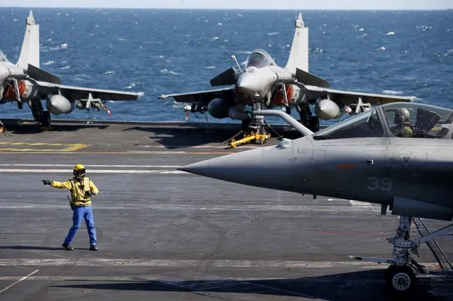 A “yellow dog” flight deck officer directs a Rafale fighter jet that prepares to take off aboard France's Charles de Gaulle aircraft carrier which continues its mission in the Gulf, January 28, 2016. (Photo by Philippe Wojazer/Reuters)
