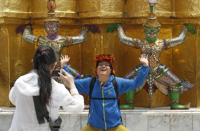 A Chinese tourist strikes a similar pose to statues as they visit the Grand Palace in Bangkok March 23, 2015. Public outrage forced the Thai government to issue thousands of Chinese-language etiquette manuals last month in an effort to ensure sightseers behave themselves. (Photo by Chaiwat Subprasom/Reuters)