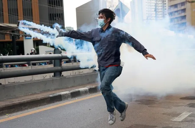 A demonstrator throws back a tear gas canister during a protest against the government's handling of the coronavirus disease (COVID-19) pandemic, in Bangkok, Thailand, August 10, 2021. (Photo by Soe Zeya Tun/Reuters)