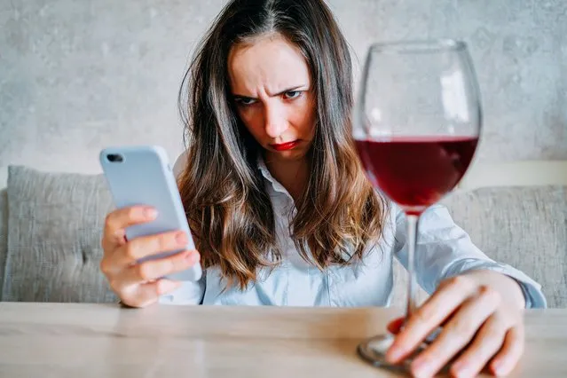 Girl drunk from wine sits and writes a message on a smartphone. (Photo by Getty Images/iStockphoto)