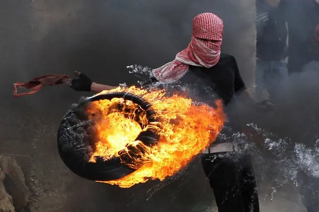 A Palestinian sets fire to a tyre during clashes between hundreds of Palestinians and Israeli soldiers outside the Ofer prison after a march marking the 65th Nakba day or “Day of Catastrophe” on May 15, 2013 in Betunia near the West Bank city of Ramallah. (Photo by Abbas Momani/AFP Photo)