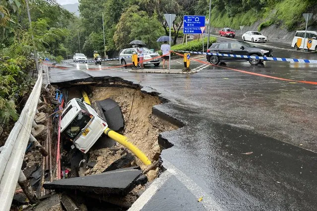 This picture shows a vehicle in a collapsed section of road in Hong Kong on September 8, 2023. Record rainfall in Hong Kong caused widespread flooding in the early hours on September 8, disrupting road and rail traffic just days after the city dodged major damage from a super typhoon. (Photo by AFP Photo/China Stringer Network)