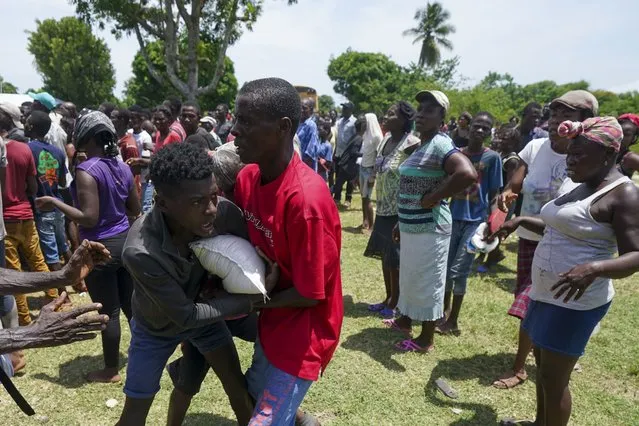 Men scuffle over a sack of donated food taken from a truck loaded with relief supplies, in Vye Terre, Haiti, Friday, August 20, 2021. (Photo by Fernando Llano/AP Photo)
