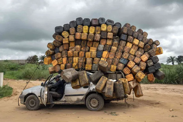 A driver carrying empty plastic containers pauses on his way to buy fuel from Angola and sell it back in Muanda, western Democratic Republic of Congo Congo, Saturday, December 23, 2023. (Photo by Mosa'ab Elshamy/AP Photo)