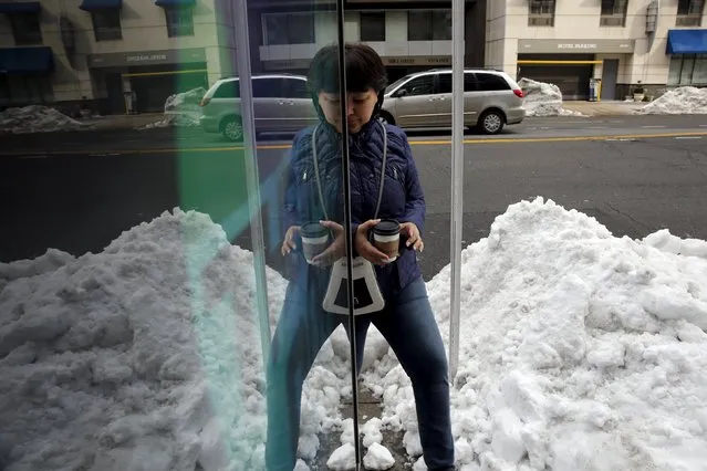 A woman walks carefully around piles of snow at a bus shelter in Washington January 26, 2016. (Photo by Jonathan Ernst/Reuters)