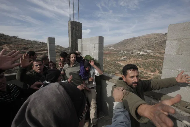 Palestinians (front and L) try to prevent fellow Palestinians from the village of Qusra from beating up a group of Israeli settlers as they are cornered at a construction site after they sparked clashes upon entering the village near Nablus, on January 7, 2014. (Photo by Jaafar Ashtiyeh/AFP Photo)